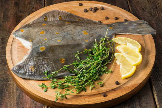 Fresh raw plaice with pepper, thyme and lemon on the board