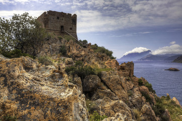 Fototapeta na wymiar A colorful coastal view with a stone tower in Corsica, France