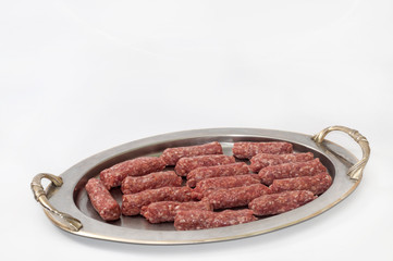 Raw kebabs aligned on the metal tray