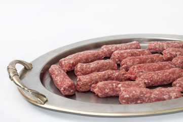 Raw kebabs aligned on the metal tray