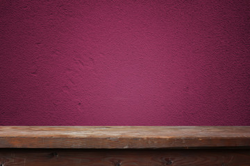 Empty wooden table against a violet wall.