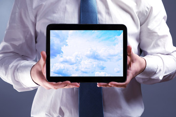 Businessman holding tablet PC with sky in screen. Cloud computing concept