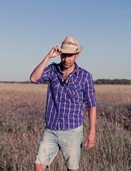 Naklejka na ściany i meble Attractive young man standing in a field. Cowboy