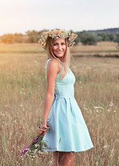 Fototapeta na wymiar Beautiful young woman with wreath of wildflowers in their hair.