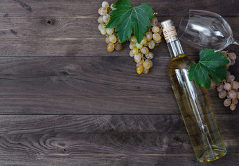 Bottle of wine and fresh grape on wooden background