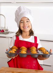 proud female child presenting muffin cakes learning baking in cook hat smiling happy