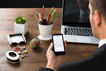 Businessman Looking At New Message On Mobile Phone