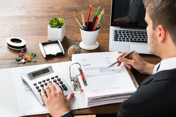 Businessman Calculating Receipt At Desk