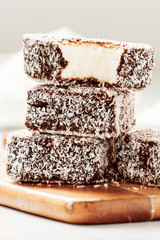 Group of Lamingtons on a timber cutting board with food ingredients in the background 