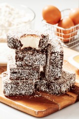 Group of Lamingtons on a timber cutting board with food ingredients in the background 