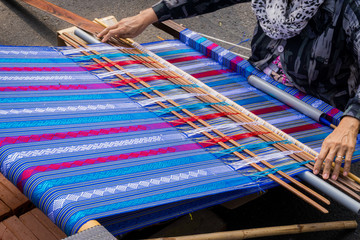 Hand of the woman weaves traditional fabric
