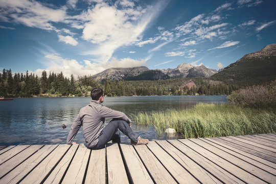 Man sitting near alpine mountain lake