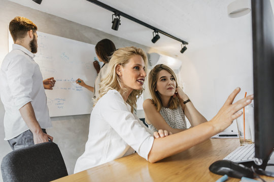 Coworkers in office pointing at desktop