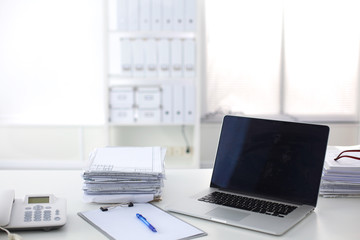 Laptop with stack of folders on table on white background