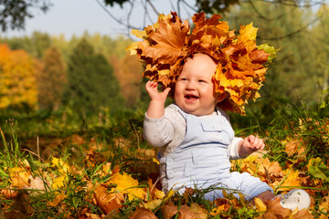 A happy, smiling boy in a wreath from autumn leaves