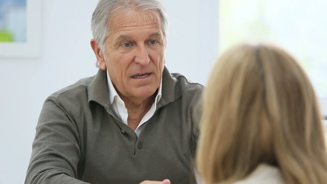 Senior man having a talk with woman sitting in front 