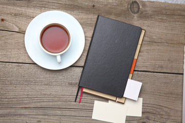 Blank business cards with pen, notebook and tea cup on wooden