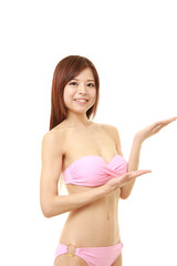 Obraz premium young Japanese woman in a pink bikini presenting and showing something