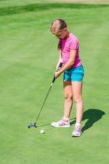 Fototapeta premium Cute little girl playing golf on a field
