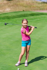 Fototapeta premium Cute little girl playing golf on a field
