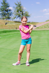 Cute little girl playing golf on a field