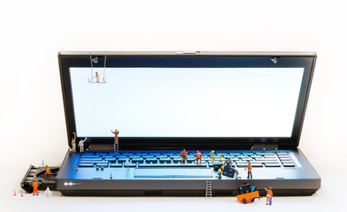 Team of Miniature workers repairing Laptop.