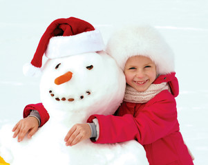 little girl hugging a snowman and laughs. Winter fun