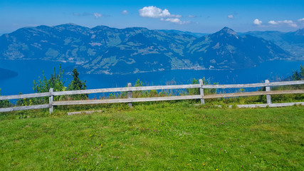 Fototapeta premium Green field surrounded by fence across the mountain