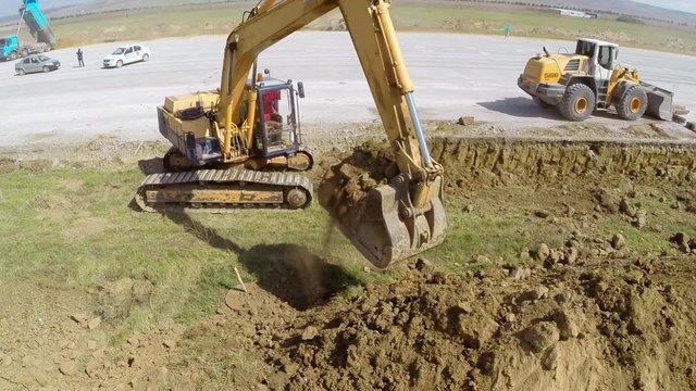 Heavy construction equipment working on an airport runway, aerial view