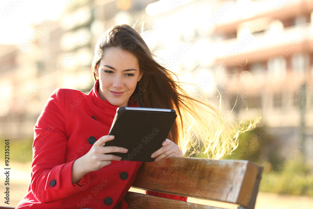 Poster woman reading an ebook or tablet in an urban park