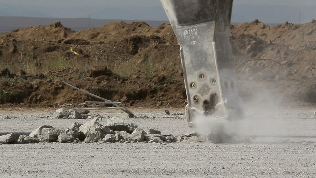 Hydraulic crushing hammer breaking concrete on an airport runway