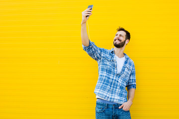 young handsome man with headphones on yellow wall