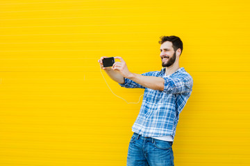 young handsome man with headphones on yellow wall