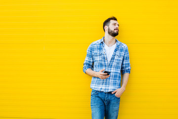 young handsome man with headphones on yellow wall