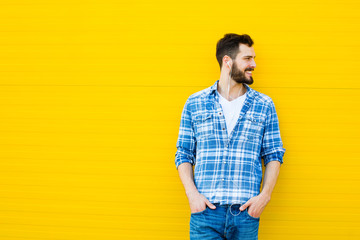young handsome man with headphones on yellow wall