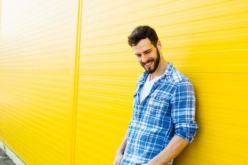 young handsome man with headphones on yellow wall