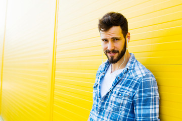 young handsome man with headphones on yellow wall