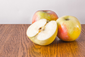 Two whole apple and half lying on a wooden table