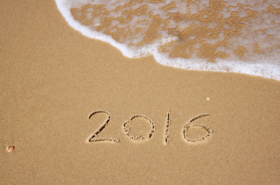 new year 2016 written in sandy beach. image is retro filtered
