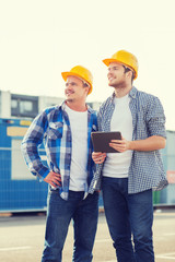 smiling builders with tablet pc outdoors