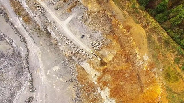 Aerial view of working excavator in the opencast mine. Camera flight over industrial landscape.