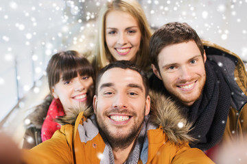 happy friends taking selfie on skating rink