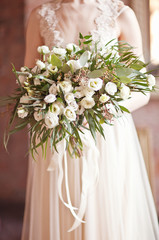 the bride holding wedding bouquet of white ranunculus, grass and roses