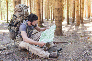 Man with Backpack and map searching directions - 92143873