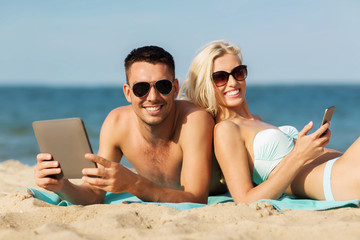 Fototapeta premium happy couple with tablet pc sunbathing on beach