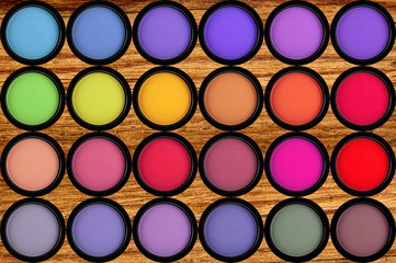 colorful eyeshadows in black boxes on the wooden background