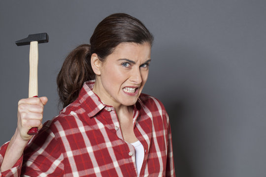 furious 30s woman holding hammer for aggression or self-defense