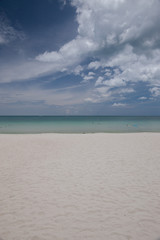 Beach on tropical island. Clear blue water, sand, clouds. 