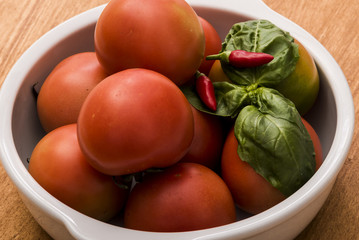 Tomatoes with basil and hot pepper in a white bowl