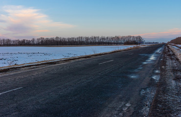 Winter landscape with an empty country road in Ukraine at evening time